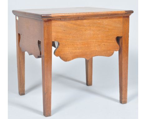 A late 18th Century George III mahogany commode having a shaped frieze and raised on squared legs, the hinged lid revealing a