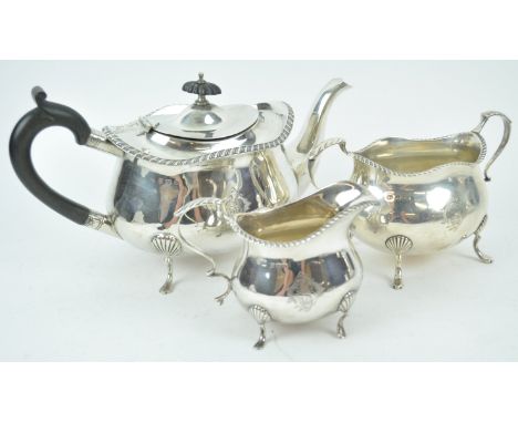 A silver three piece tea service, of shaped oval form, the undulating rope edged top over a plain bevelled body, raised on fo