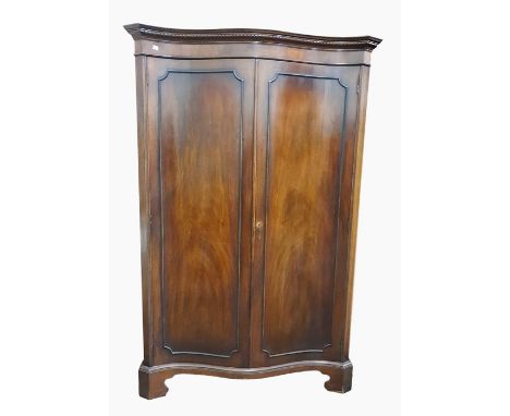 Georgian style mahogany serpentine-front wardrobe with dentil cornice, the pair of panelled doors enclosing shelf and hanging