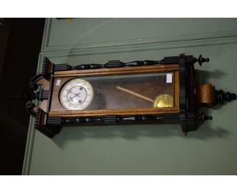AN EARLY 20TH CENTURY WALNUT AND EBONISED WALL CLOCK, by Junghans, with two stage enamel dial and Arabic numerals, inside an 