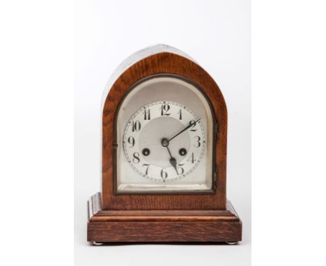 AN OAK LANCET SHAPED MANTEL CLOCK, by Junghans circular silverised dial with Arabic numerals, on rectangular moulded base, 12