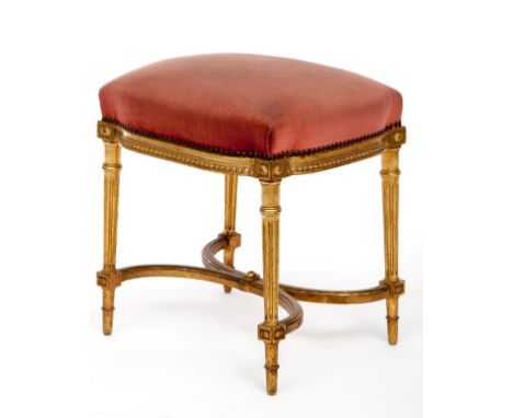 A FRENCH GILT STOOL, with padded seat and tongue and dart moulded apron, raised on turned and fluted legs, united by an X-fra