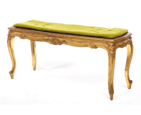 AN OBLONG GILT WINDOW STOOL, of serpentine form, with cane seat and shaped floral moulded apron, raised on moulded cabriole l