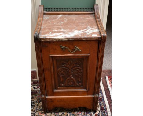 AN EDWARDIAN WALNUT PERDONIUM, with rouge and white speckled marble top, and a brass gallery, the drop-front panel carved wit