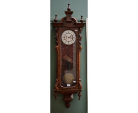 A VICTORIAN FIGURED WALNUT VIENNA STYLE WALL CLOCK, with arched pediment and three urn finials, above a two-stage enamel dial