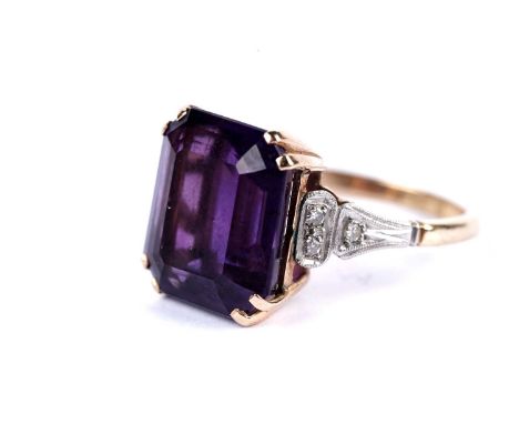 An amethyst and diamond dress ring, the truncated step cut amethyst on diamond set shoulders, the yellow gold shank stamped "