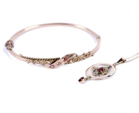 An Edwardian 9ct rose gold bangle, with a central star set diamond flanked by star set red stones, 66mm wide, with safety cha
