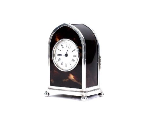 A George V silver mounted tortoiseshell desk timepiece in the shape of a gothic arch, on four bun feet, the white enamelled d