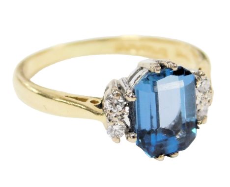 An 18ct gold, topaz and diamond set ring, the emerald cut topaz flanked by two pairs of brilliant cut diamonds, size I, 3.0g.