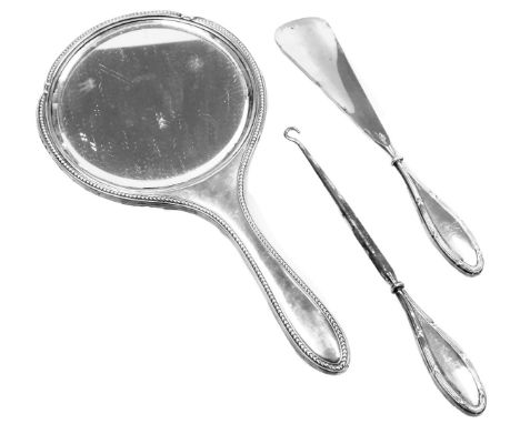 A George V silver backed hand mirror, Chester 1915, together with a silver handled shoe horn, Birmingham 1922 and button hook