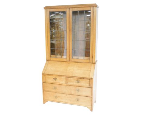 An early 20thC oak bureau bookcase, with an out swept pediment over two leaded glazed doors enclosing two shelves, the bureau