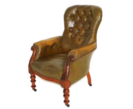 A Victorian mahogany and tan leather balloon back armchair, with button back, foliate carved scroll arms, raised on turned le