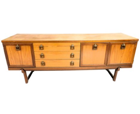 A mid century teak sideboard, with three drawers flanked to the left by a drop down drinks cabinet, to the right by a pair of