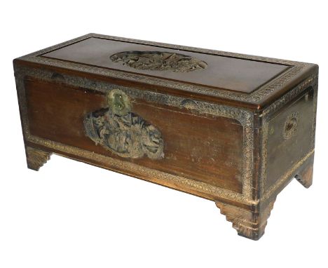 An early 20thC Chinese camphor wood chest, with a figural carved hinged lid, and front, the borders carved with flowers, rais