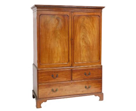 A George III mahogany linen press, the out swept pediment over a pair of panelled doors enclosing a later interior, above two