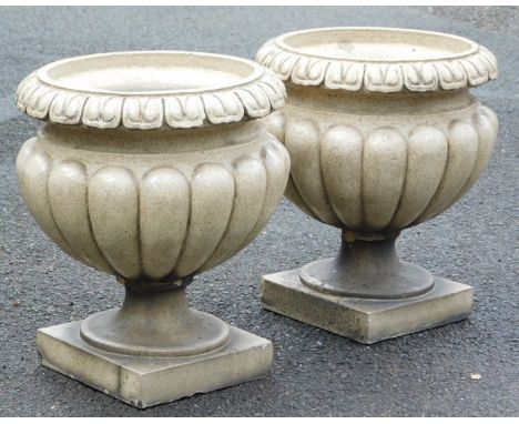 A pair of mottled brown and cream stoneware garden urns, of semi fluted form, with a lappet border, raised on a square base, 