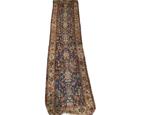 A Persian silk runner with an all over foliate design over a deep blue field, with a complementary border on a biscuit ground