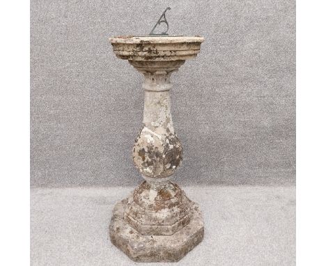 A carved stone sundial with a patinated bronze plate on a turned top above a baluster form stem on an octagonal plinth base. 