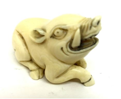 A Meiji Period Ivory Netsuke:Carved as a recumbent boar with mouth open showing tusks.Height 3 cm Width 4.5 cm   CONDITION RE