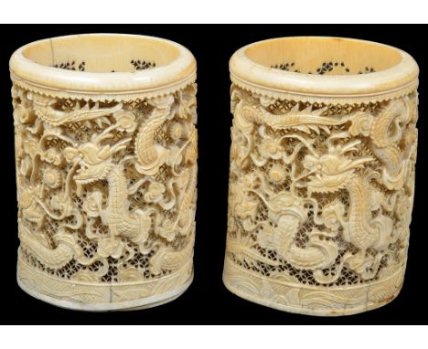 A pair of Chinese ivory brush pots19th centuryReticulated and carved in high relief with sinuous dragons chasing a flaming pe