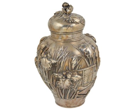 A Japanese Embossed Silver Tea caddy:Heavily embossed caddy with water iris flowering around the wooden boards of a walkway i