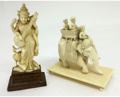 Two c1920s Ivory Carvings:One of an Indian deity with four arms playing a sitar with a peacock at her side, the other an elep