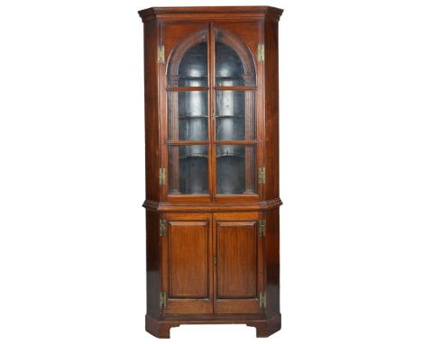 A Corner Cabinet:18th/19th century, mahogany, the glazed doors opening to reveal a carved arch shape pilaster above two panel