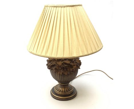 A composite wood effect table lamp, the reeded bulbous body detailed with oak leaves and acorns, upon spreading circular base