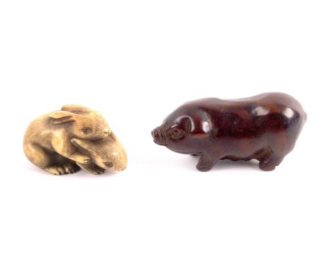 Two Japanese netsuke late 19th/early 20th Century, comprising a wooden example in the form of a pig, 6.5cms, and another in i