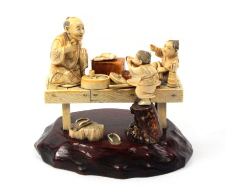 A late 19th Century Japanese sectional ivory figure group of a man and two children, fixed to an oval carved wood base. The m