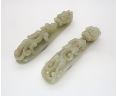 TWO CHINESE JADE BUTTON HOOKS each carved with a chilong beneath an animal head terminal, 12cm long and 12.5cm long (2) Condi