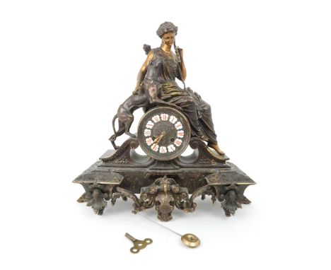 A FRENCH PATINATED SPELTER MANTLE CLOCK modelled as Diana holding a bow with a dog at her side, the dial with enamelled Roman