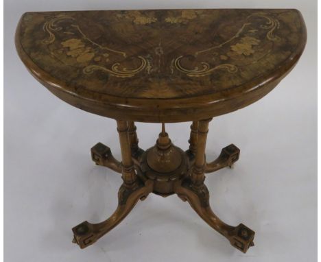 A VICTORIAN BURR WALNUT AND MARQUETRY INLAID DEMI LUNE FOLD OVER CARD TABLE  on turned supports above carved quadripartite ba