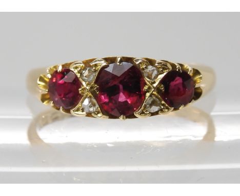 AN 18CT GOLD RUBY AND DIAMOND ACCENT RING hallmarked Chester 1897, the largest ruby measures 5mm x 4.6mm x 3mm, interspaced w