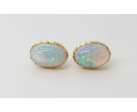 A PAIR OF JELLY OPAL EAR STUDS  dimensions of the opals 10.5mm x 7.5mm, in yelow metal cut back mounts with post and butterfl