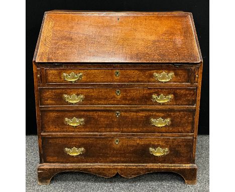 A George III oak bureau, fall front enclosing a fitted architectural interior, above four long graduated cockbeaded drawers, 