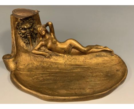 An Art Nouveau bronze inkwell, cast as a female nude, reclining beside a fountain head, depicting Bacchus, signed in the maqu