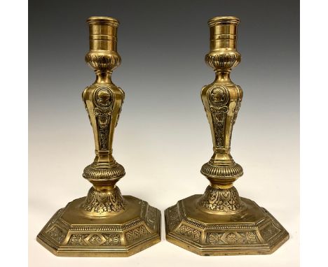A pair of 18th century French brass table candlesticks, of seamed construction, cast with portrait roundels, swags, and panel