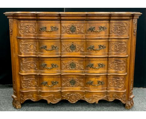 A Louis XV Revival carved oak commode chest, the shaped over-sailing top with a moulded frieze, over four long drawers, with 
