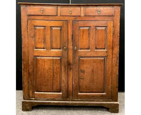 An early 18th century panelled oak provisions cupboard, the top frieze having three short drawers, above a pair of large cupb