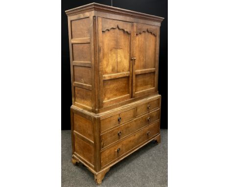 A George III oak linen press, the out-swept cornice above a pair of cupboard doors with shaped panels, and four-panel sides, 