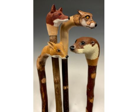 A group of four hand-carved walking canes / walking sticks, three with the handles carved and painted as the head of a Fox, i