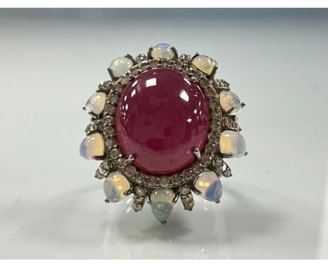 A large oval ruby opal and diamond cluster ring, central cabochon ruby 21.64ct, surrounded by alternating petals of pear opal