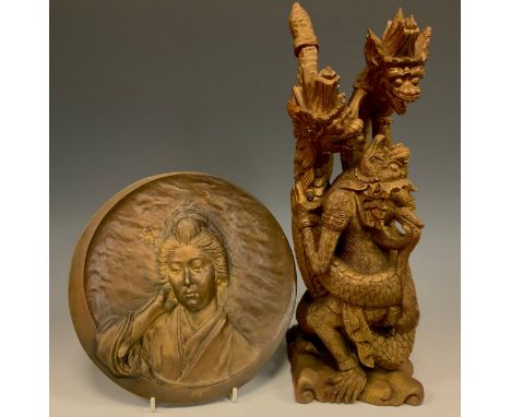A Japanese Bronze circular plaque, with a Portrait of a Geisha, cast in high relief, within a ‘Crescent moon’ border, 24cm di