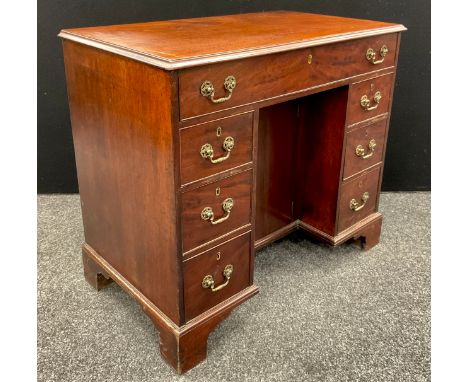 A George III mahogany kneehole desk, rectangular moulded top above a cock beaded long drawer and three small conforming to ea