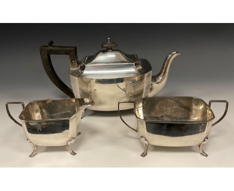 A George V silver three piece tea set, of canted rectangular form, the teapot with ebony handle and finial, square pad feet, 