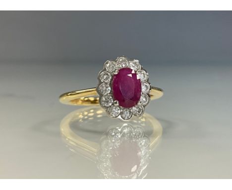 A ruby and diamond cluster ring, oval pinky red ruby approx 1.02ct, surrounded by twelve round brilliant cut diamonds, total 