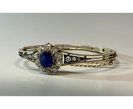 A sapphire and diamond hinge bangle, central vibrant blue circular sapphire approx 1.90ct, surrounded by ten old mine cushion