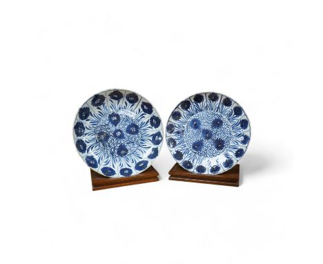 Two Chinese blue and white ‘astor’ plates, Kangxi period, with hardwood stands, largest 22cm diameter. Condition - poor to fa