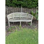 A curved teak bench, 160cm, 82cm high. Condition - weathered, otherwise good